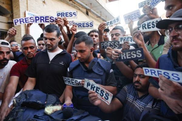 Mourners and colleagues holding 'press' signs surround the body of Al-Jazeera Arabic journalist Ismail al-Ghoul, killed along with his cameraman Rami al-Refee in an Israeli strike during their coverage of Gaza's Al-Shati refugee camp, on July 31, 2024. - Al Jazeera co<em></em>ndemned the killing of two of its journalists, calling the deaths a "cold-blooded assassination" in a statement. (Photo by Omar AL-QATTAA / AFP)