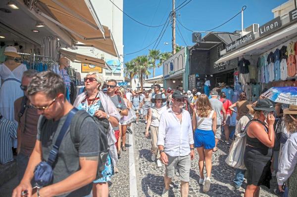 Tourists walking through a street in the village of Fira on Santorini recently. Like other popular tourist destinations, the island is approaching over-crowding. — Photos: AFP